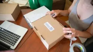 Nhân sự đóng gói đơn hàng với laptop minh họa form báo giá và task sales