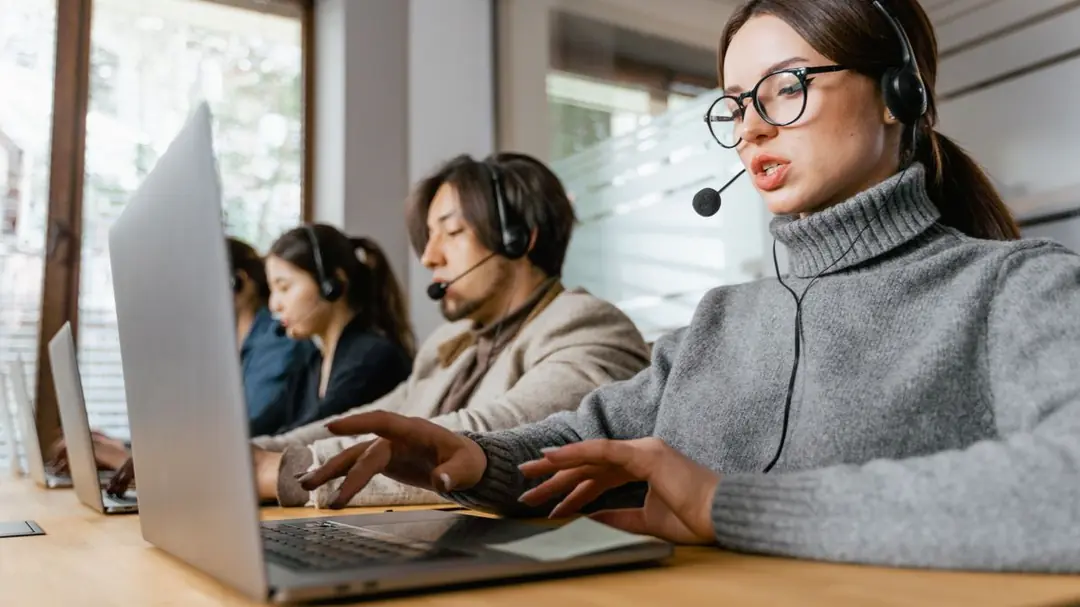 nhóm nhân viên hỗ trợ khách hàng đeo headset làm việc với laptop trong crm logistics
